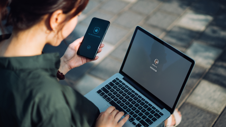 A person holding a phone and a laptop
