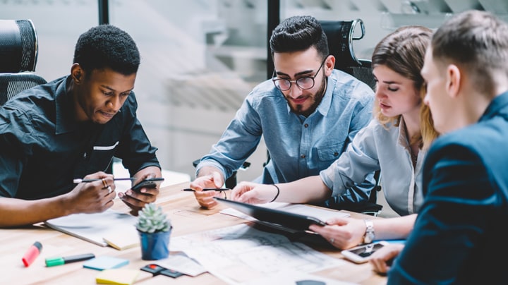 3 people working on a tablet, 1 person looking at a phone