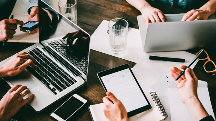 Gruppe von Personen, die an Laptops und Geräten arbeiten