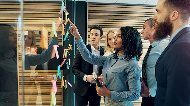 un grupo de profesionales trabajando juntos en una pared de cristal de notas post it