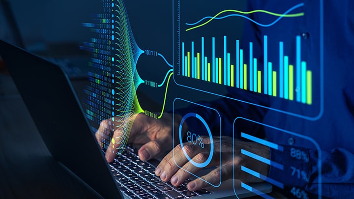 A person working a laptop with graphs and charts in the foreground