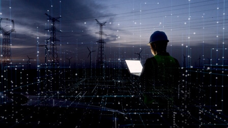 Worker with tablet near wind turbines and power lines at dusk