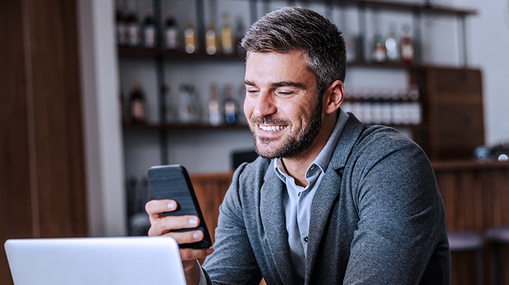 Professionelle Person, die ihr Mobiltelefon lächelnd in der Hand hält.