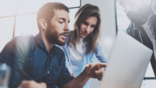 Coworkers looking at data on laptop