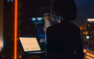 Woman in the dark looking out the window