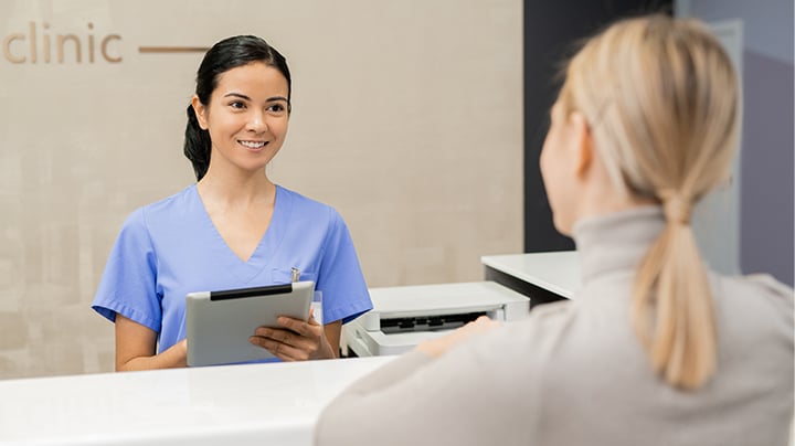 Person speaking to a medical professional behind a desk