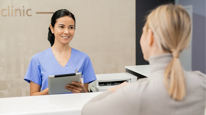 Pessoa falando com um profissional médico atrás de uma mesa