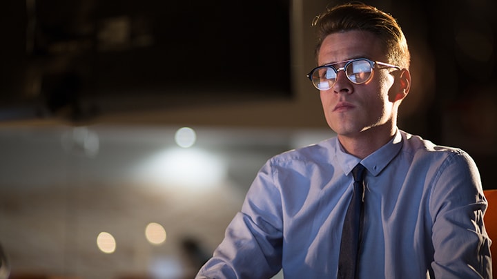 Man wearing glasses staring at screen in dark office