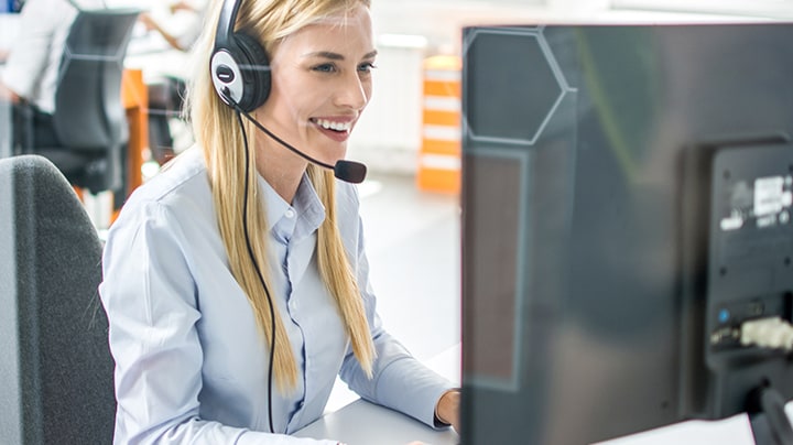 Arbeiter, die über ein Headset sprechen, während sie vor einem Computer sitzen