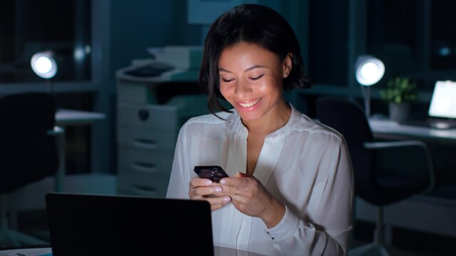 Femme utilisant un téléphone devant un ordinateur portable