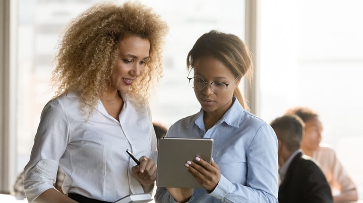 Two people reviewing outbound communications on a tablet in the office