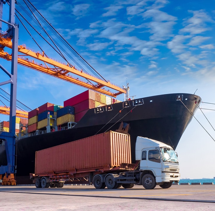 Cargo ship at dock with transport truck in foreground