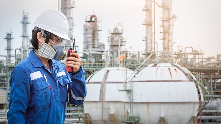 Person with personal protective gear on talking into a two-way radio