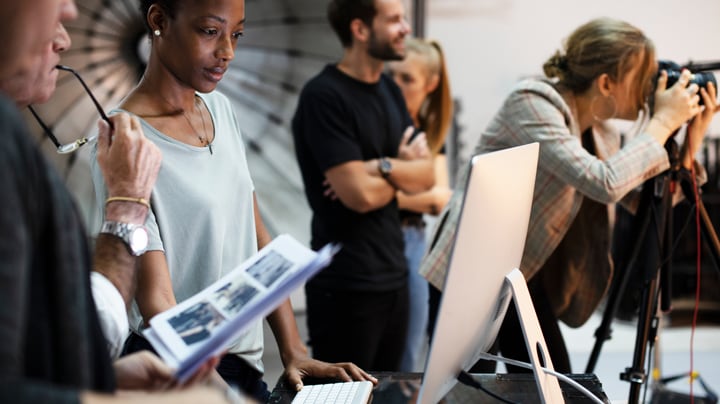 Creative team looking at photos, photographer in background