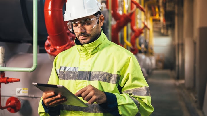 A man in his safety gears looking in his tablet.