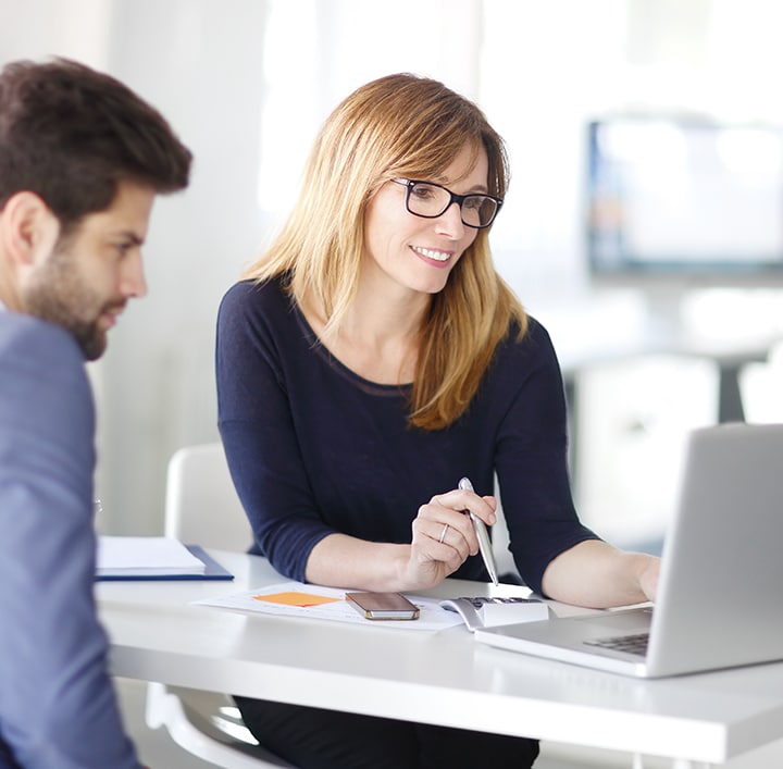  Um homem e uma mulher discutindo com um laptop e usando uma calculadora.