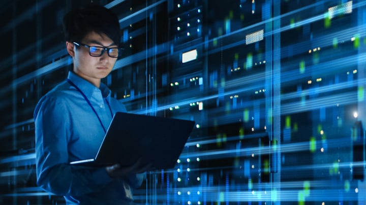 IT team member checks laptop in massive server facility