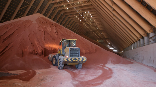 Loader moving large piles of red material inside a warehouse