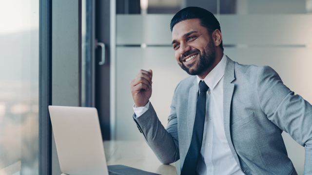 The smiling person working at a desk with a laptop, confidently glancing to the side