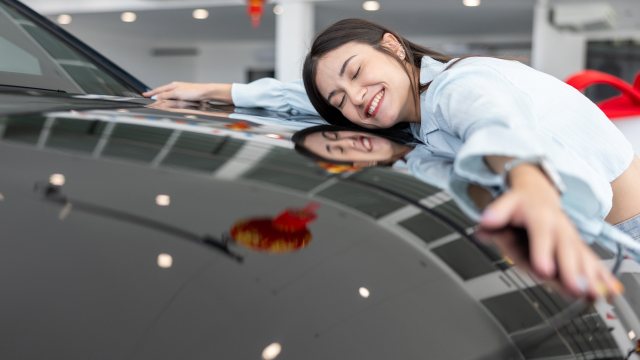 Smiling person hugging their car joyfully