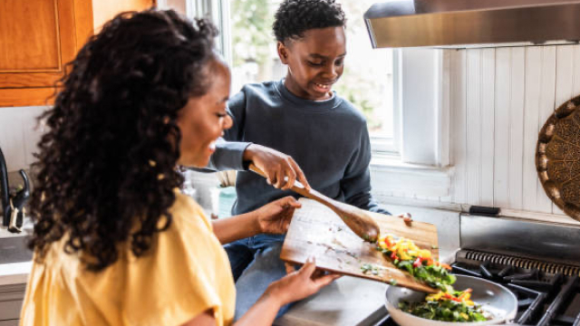 Two people preparing a meal on the stove