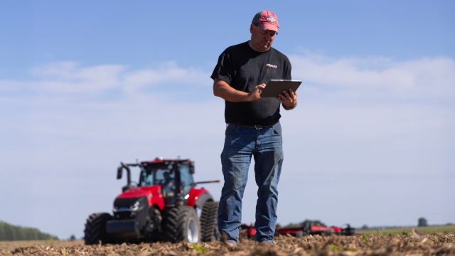A farmer in a field looking at a tablet
