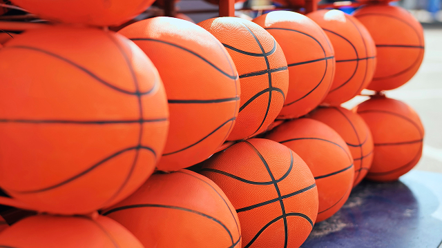 Collection of orange basketballs stacked at a sports court