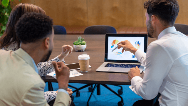 A group of business people collaborating and pointing at a computer screen in an office