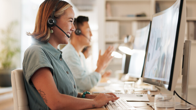 Customer support agents wearing headsets working at computers