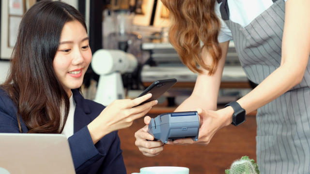 Woman using her smartphone to make a contactless payment