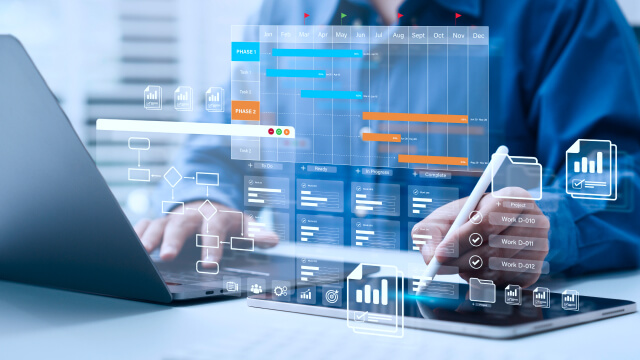 Person using a laptop and tablet with digital project management and analytics dashboards overlaid