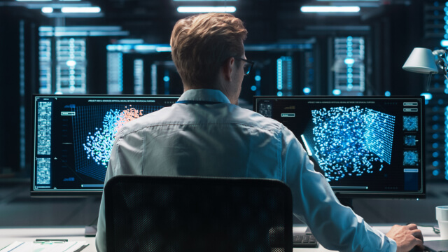 A person analyzing data on multiple monitors in a control room
