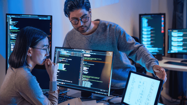 Two people reviewing code on their computers together