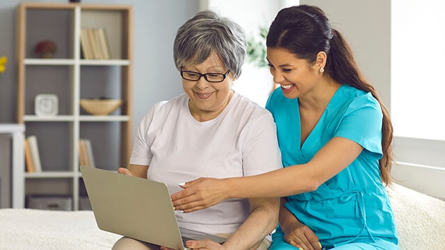 A nurse showing something to a patient on a laptop.