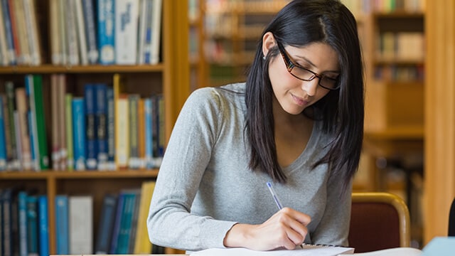 A person writing in the booklet.