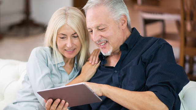 A man and a women looking at a tablet.