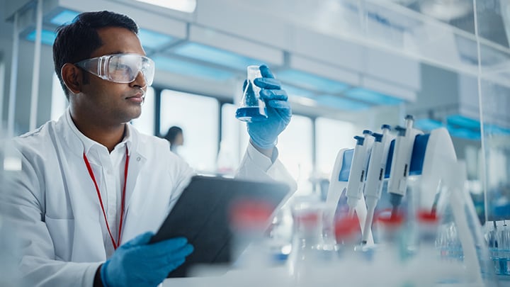 Medical technician in lab holding beaker