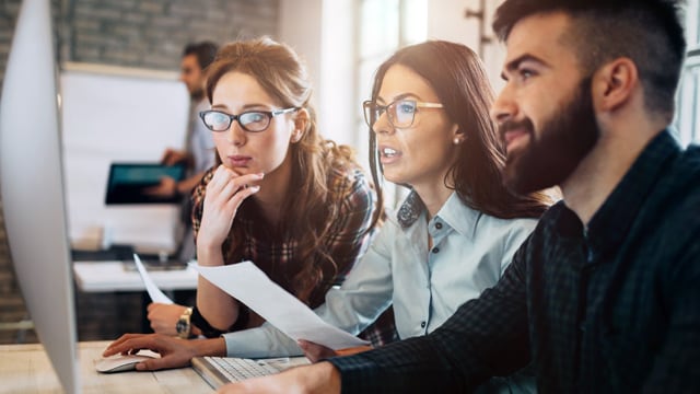 Three people in office looking at computer