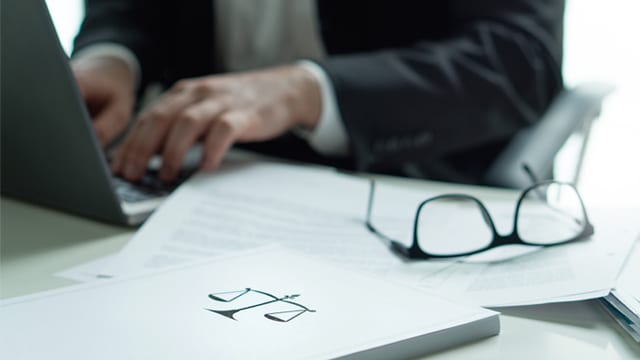 Person working on laptop with legal documents on desk