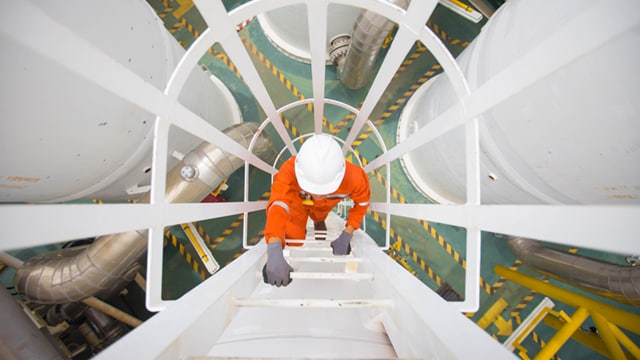 Man in safety gear and hardhat climbing ladder