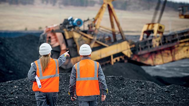 Two people in safety vest and hardhat at a mine