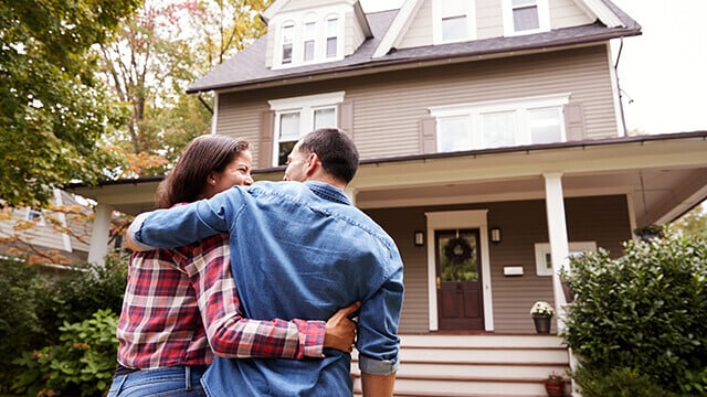 A couple walking in front of home.