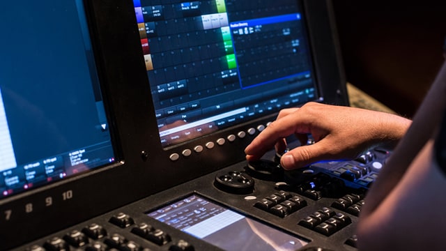 Close up of person's hands using audio and visual mixing board.