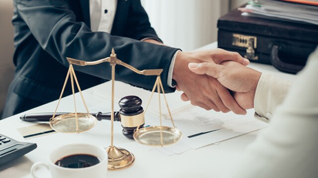 People handshaking over table with scales in foreground.