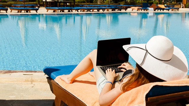 Reclining with laptop by swimming pool