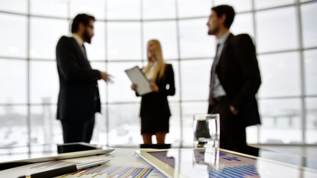 Three people having a discussion in a boardroom