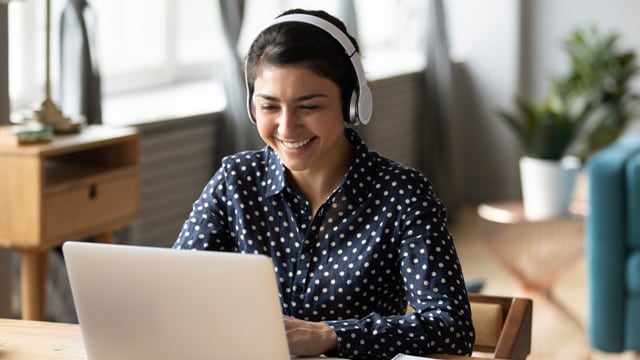 Woman using laptop wearing headphones