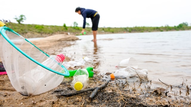 person cleaning up litter at lake