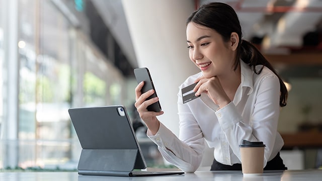 Women looking a phone while holding a credit card.