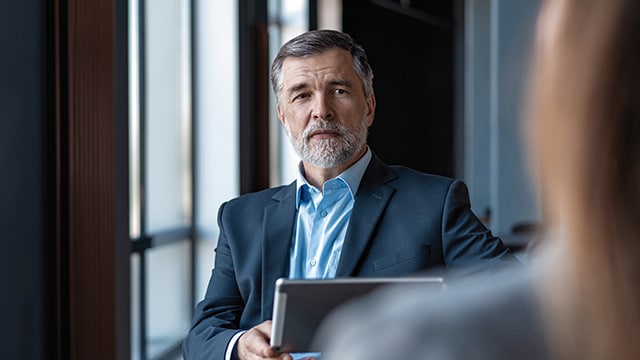 A man with a suit on sitting at a table.